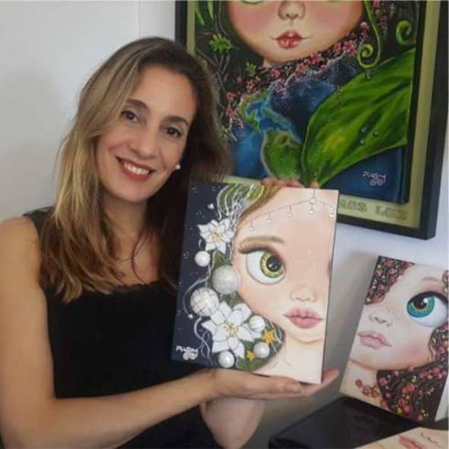 Paola sonriendo en su taller de arte rodeada de pinceles y pinturas